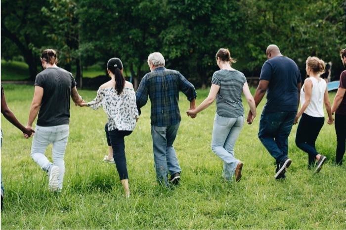 Group of People Walking Away From the Camera Hand in Hand